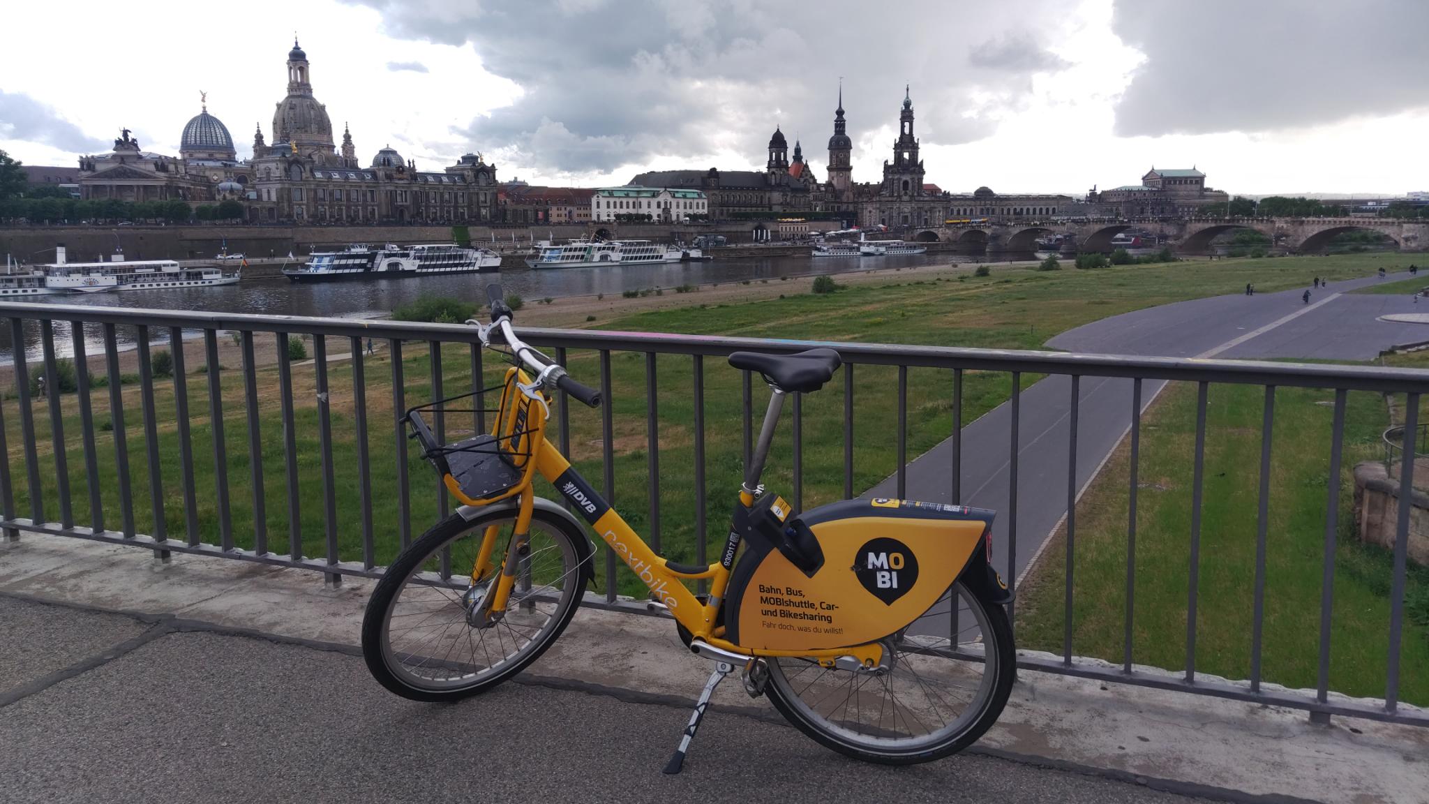 The photo shows a MOBIbike on the Carolabrücke with Dresden's Old Town in the background